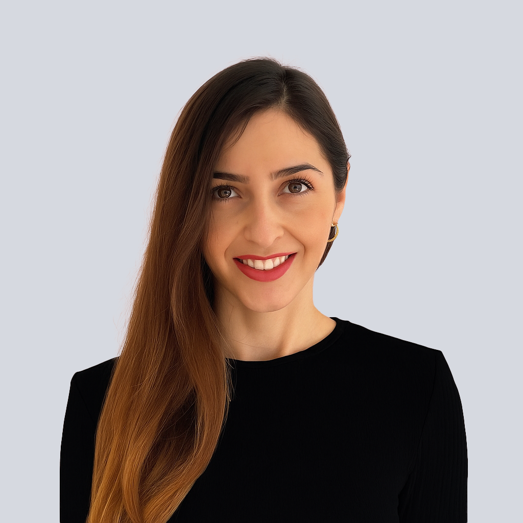 Portrait of a woman with brown hair on a flat gray background.